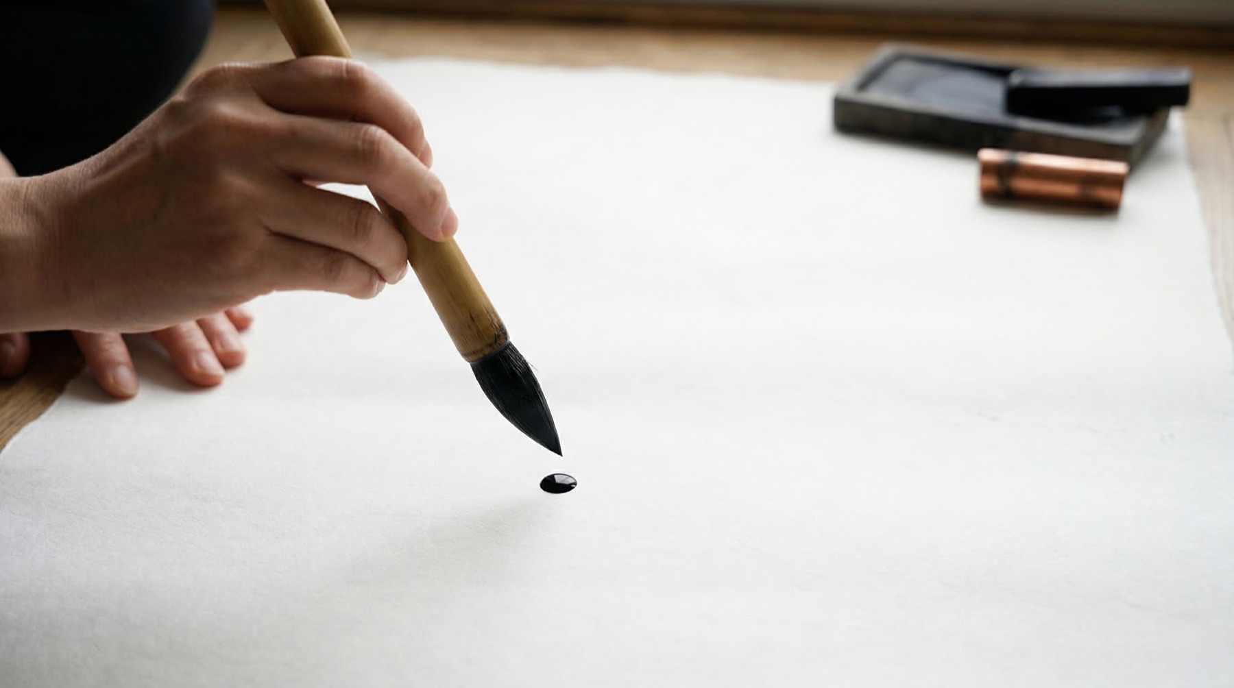 Calligrapher's hand — brush poised above paper, ink drop suspended